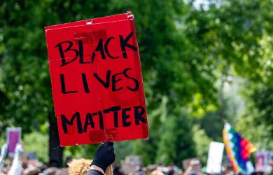 Red sign is held up from a crowd, and it read Black Lives Matter.