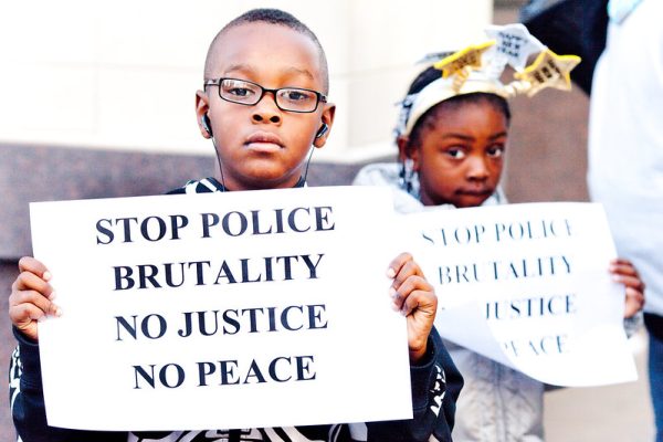 Young black boy holding a sign saying stop police brutality, no justice, no peave